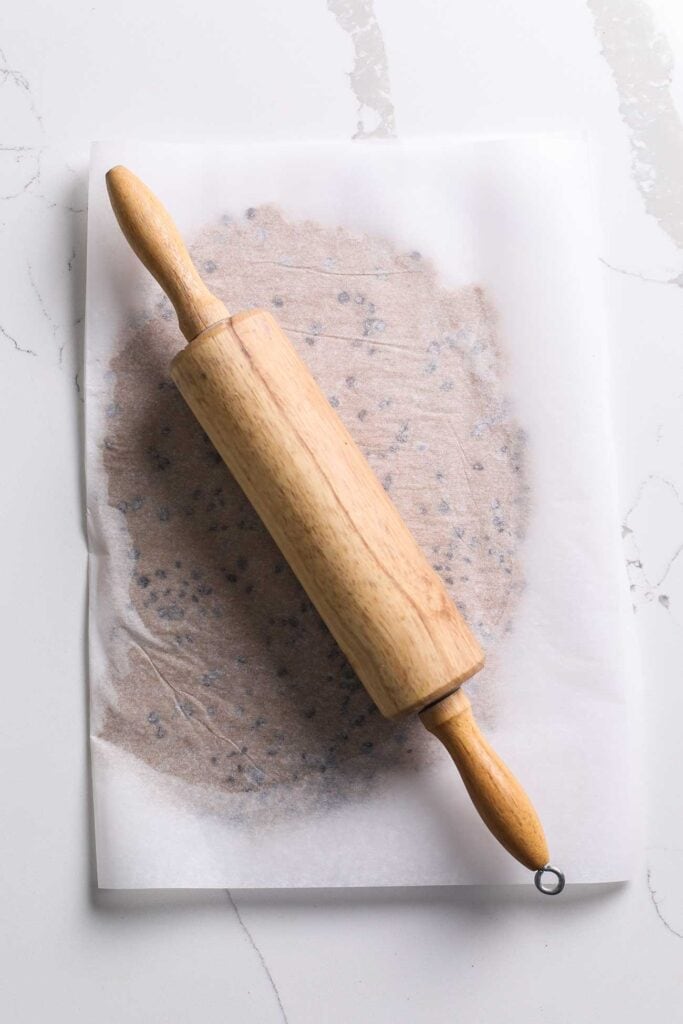 Cookie dough rolled out between two pieces of parchment paper.