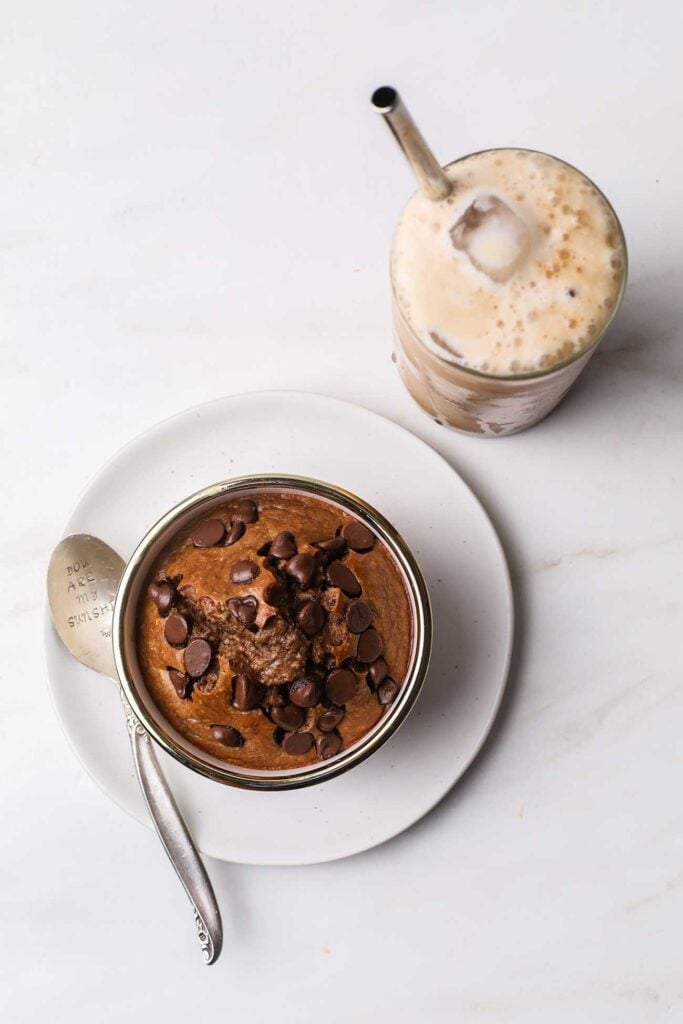 A chocolate baked oats cake next to a protein iced coffee.