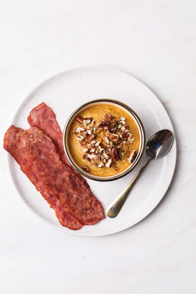 Pumpkin baked oats next to a serving of turkey bacon.
