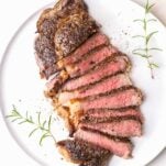 A perfect ribeye steak cooked medium rare, cut into slices on a plate.