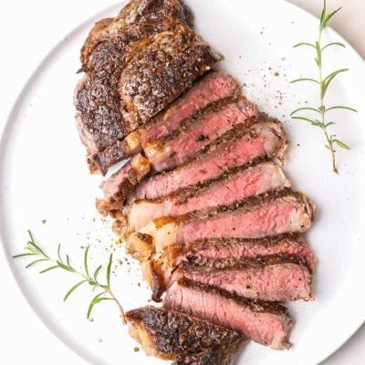 A perfect ribeye steak cooked medium rare, cut into slices on a plate.