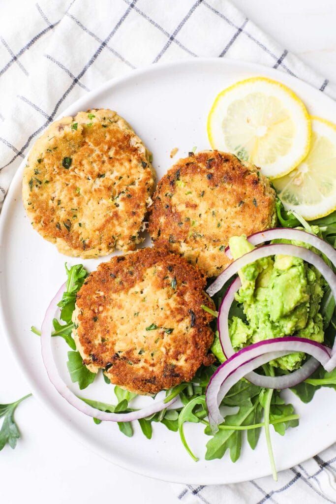 A close up look at golden salmon patties served with greens.