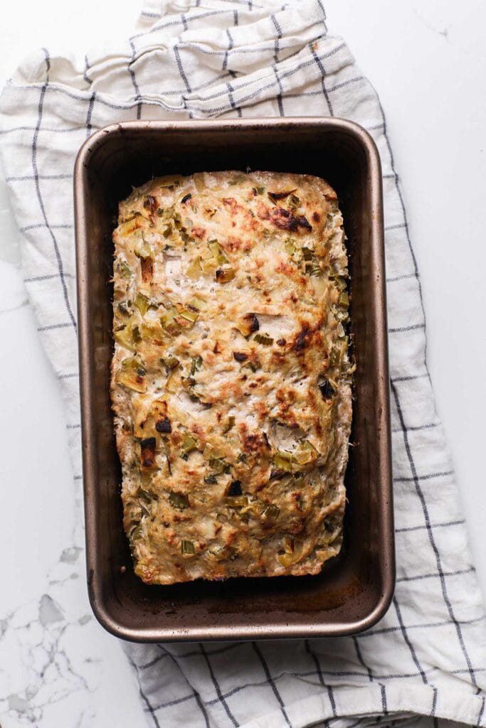 A chicken meatloaf shown baked and browned in a loaf pan.
