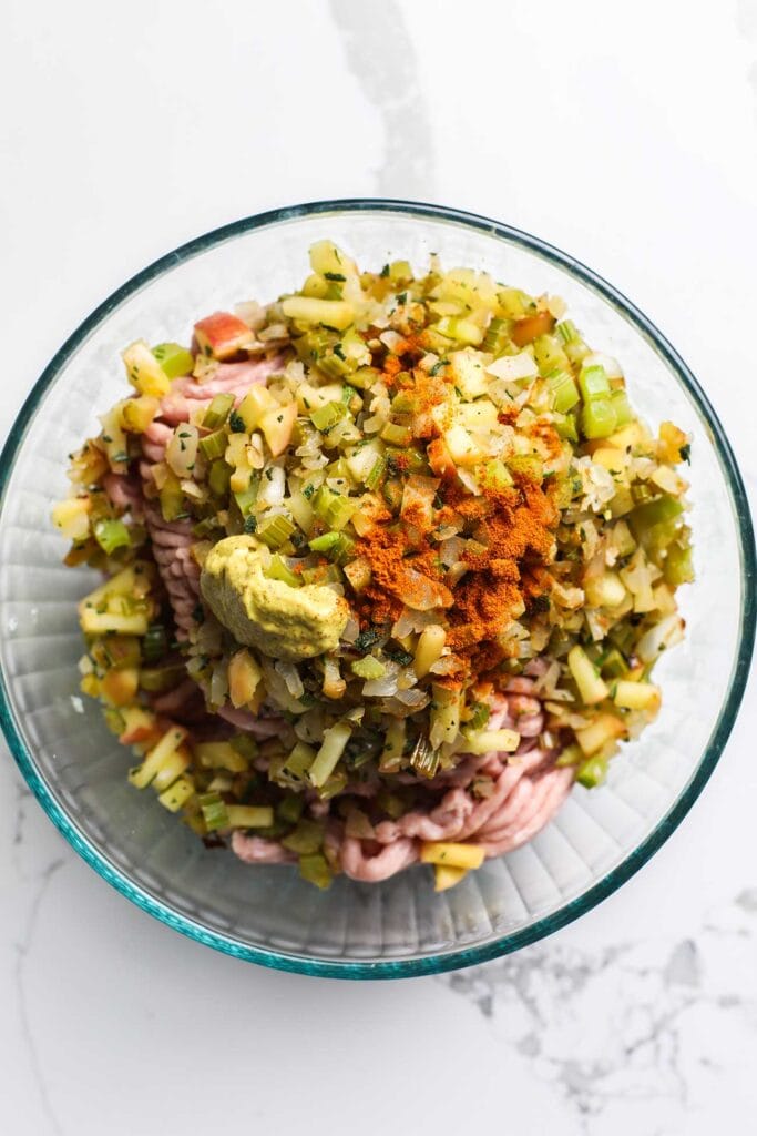 A bowl with ground chicken, sauteed vegetables, dijon mustard, and cayenne pepper.