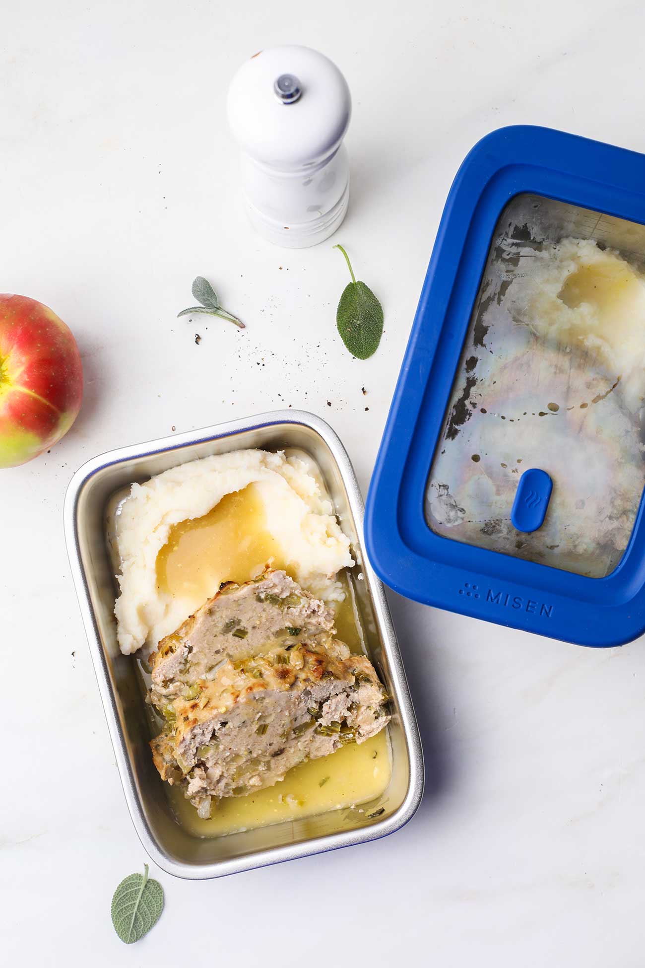 Chicken meatloaf served over cauliflower mash shown in a stainless steel meal prep container.