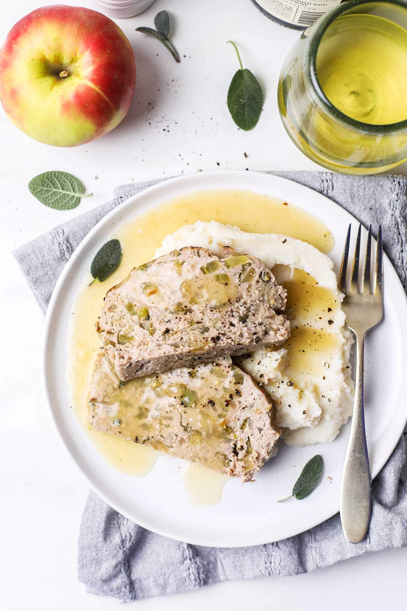 Two slices of chicken meatloaf shown served over cauliflower mashed potatoes with an apple cider gravy.