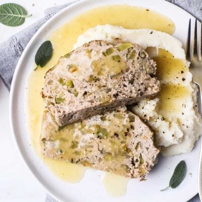 Two slices of chicken meatloaf drizzled with an apple cider gravy, over a creamy cauliflower mash.